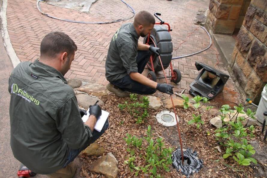 The Relining Company employees fixing an outdoor pipe drain