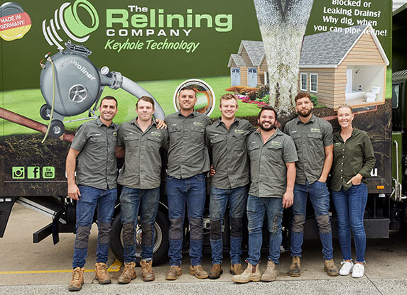 A group of 7 Relining Company employees in front of a truck