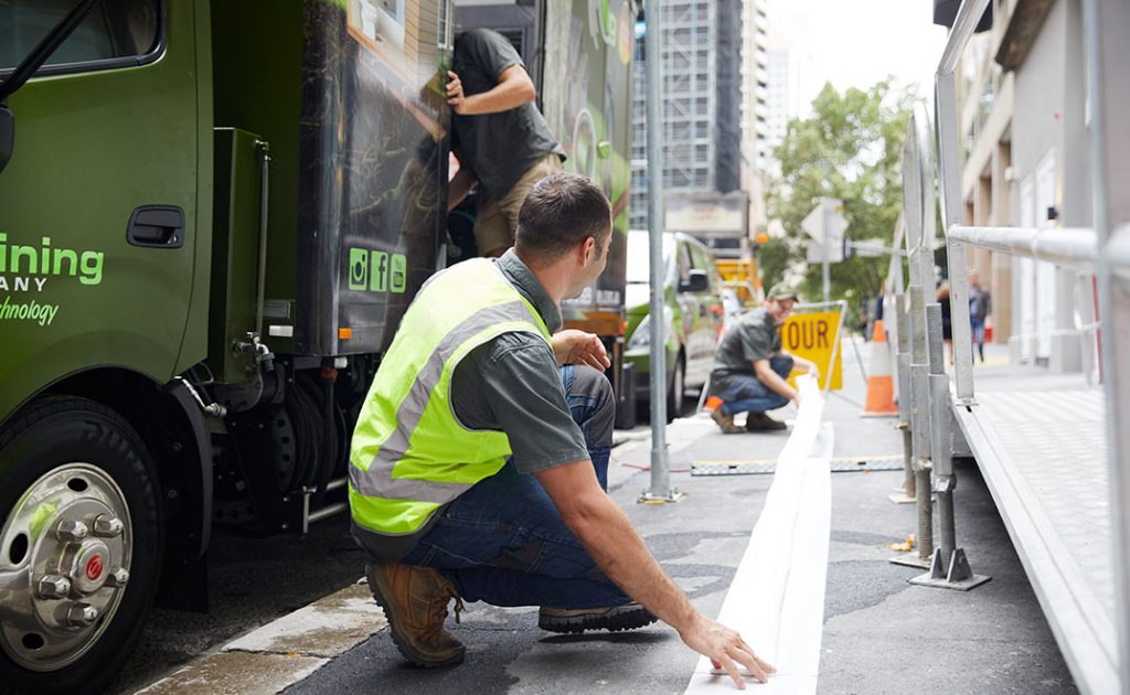 Two pipe relining company employees taping down a line outside