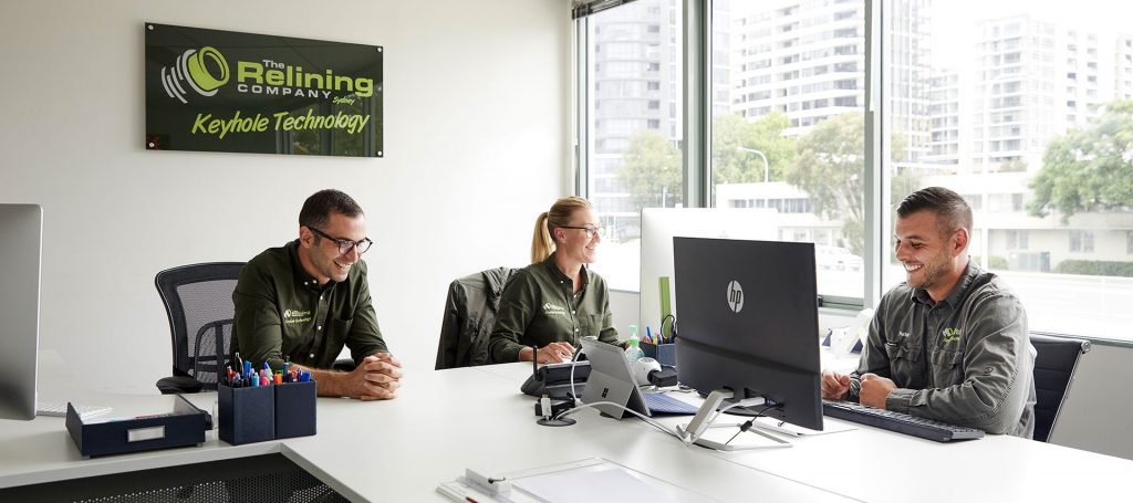 Three Relining Company employees smiling and working in the office