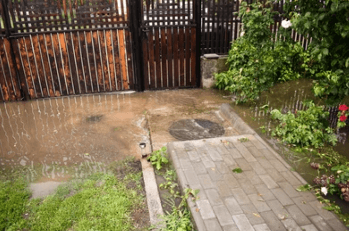 A small fenced in yard overflowing with sewer water