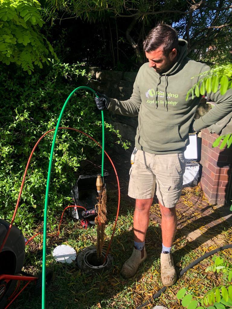 A pipe relining company employee standing outside by a drain