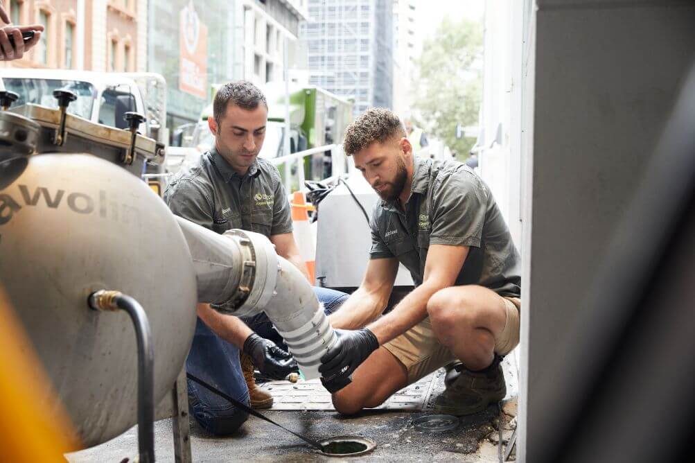 Two men repairing drain pipe under concrete