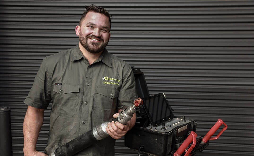 Relining company employee smiling and holding water jet blaster