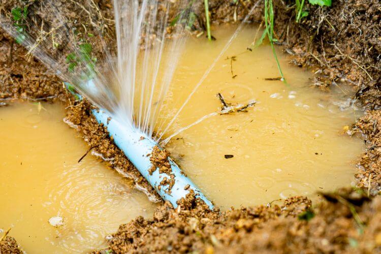 Bursted pipe, spraying out water, laying in a pool of water